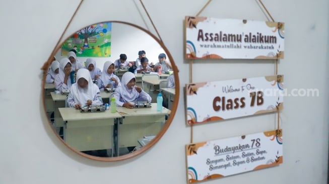 Para siswa menyantap menu Makan Bergizi Gratis (MBG) di SMPN 1 Tamansari, Bogor, Jawa Barat, Selasa (16/12/2025). [Suara.com/Alfian Winanto]