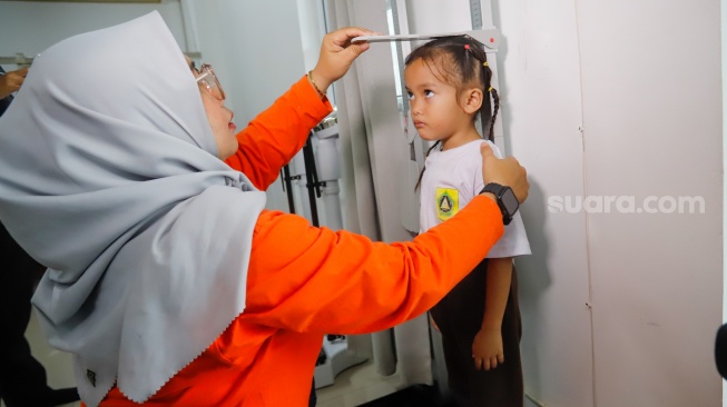 Petugas melakukan pemeriksaan kepada anak-anak dalam kegiatan Cegah Stunting (Centing) yang digelar di Jimmy Hantu Foundation, Kecamatan Tamansari, Kabupaten Bogor, Jawa Barat, Selasa (16/12/2025). [Suara.com/Alfian Winanto]
