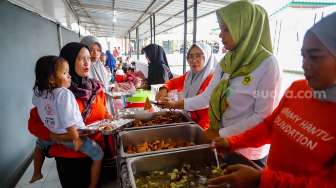 Sejumlah orang tua memberikan Makan Bergizi Gratis (MBG) kepada anak-anak dalam kegiatan Cegah Stunting (Centing) yang digelar di Jimmy Hantu Foundation, Kecamatan Tamansari, Kabupaten Bogor, Jawa Barat, Selasa (16/12/2025). [Suara.com/Alfian Winanto]