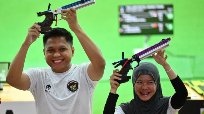 Ekspresi Dua petembak Indonesia Muhammad Iqbal Raia prabowo (kiri) dan Arista Perdana Putri Darmoyo (kanan) usai meraih medali emas pada final nomor 10 meter Air Rifle tim campuran cabang menembak SEA Games 2025 di Photharam Shooting Range, Bangkok, Thailand, Senin (15/12/2025). [ANTARA FOTO/Nova Wahyudi/tom]