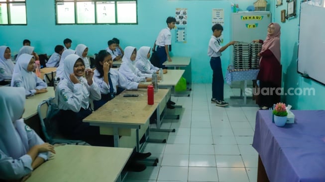 Siswa membagikan menu Makan Bergizi Gratis (MBG) untuk dibagikan ke kelas masing-masinh di SMPN 1 Tamansari, Bogor, Jawa Barat, Selasa (16/12/2025). [Suara.com/Alfian Winanto]
