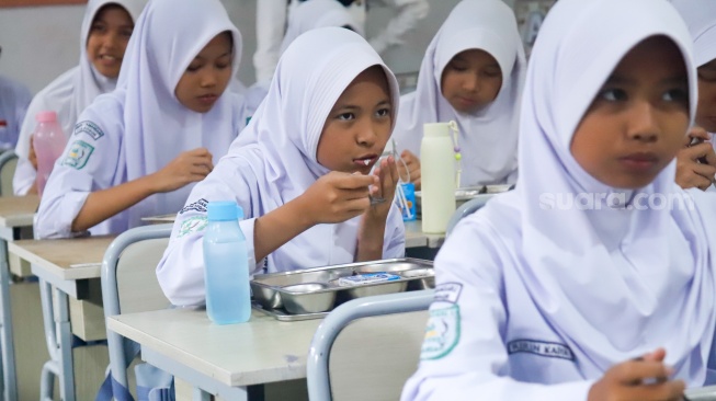 Siswa menyantap menu Makan Bergizi Gratis (MBG) di SMPN 1 Tamansari, Bogor, Jawa Barat, Selasa (16/12/2025). [Suara.com/Alfian Winanto]
