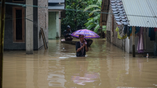 Warga berjalan menerobos banjir di Kampung Kajaroan, Cinangka, Kabupaten Serang, Banten, Kamis (18/12/2025). [ANTARA FOTO/Muhammad Bagus Khoirunas/YU]