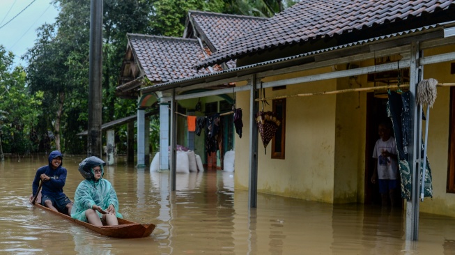 Warga menggunakan perahu kayu menerobos banjir di Kampung Kajaroan, Cinangka, Kabupaten Serang, Banten, Kamis (18/12/2025). [ANTARA FOTO/Muhammad Bagus Khoirunas/YU]