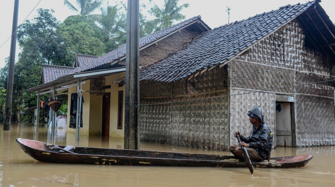 Warga menggunakan perahu kayu menerobos banjir di Kampung Kajaroan, Cinangka, Kabupaten Serang, Banten, Kamis (18/12/2025). [ANTARA FOTO/Muhammad Bagus Khoirunas/YU]