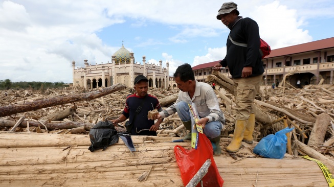 Petugas Kementerian Kehutanan dan Dinas Kehutanan Provinsi Aceh mengambil sampel kayu gelondongan yang terbawa arus luapan Sungai Tamiang, di area pasantren Islam Terpadu Darul Mukhlishin, Desa Tanjung Karang, Aceh Tamiang, Aceh, Jumat (19/12/2025). [ANTARA FOTO/Irwansyah Putra/nym]