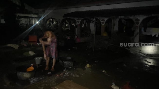 Mirza saat mandi membersihkan diri di sumur halaman Musala Gampong Dayah Husein, Meurah Dua, Pidie Jaya, Senin (15/12/2025) malam. [Suara.com/Iskandar]