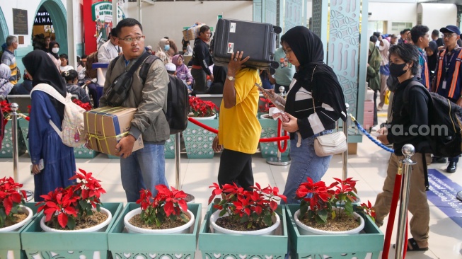 Penumpang menunggu kedatangan kereta api di Stasiun Pasar Senen, Jakarta Pusat, Senin (22/12/2025). [Suara.com/Alfian Winanto]
