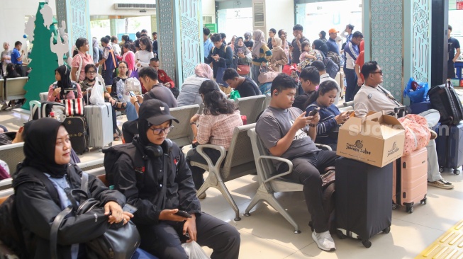 Penumpang menunggu kedatangan kereta api di Stasiun Pasar Senen, Jakarta Pusat, Senin (22/12/2025). [Suara.com/Alfian Winanto]