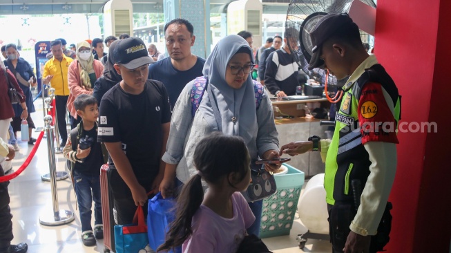 Penumpang menunggu kedatangan kereta api di Stasiun Pasar Senen, Jakarta Pusat, Senin (22/12/2025). [Suara.com/Alfian Winanto]