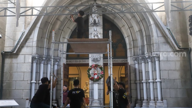 Petugas memasang dekorasi di Gereja Katedral, Jakarta, Selasa (23/12/2025). [Suara.com/Alfian Winanto]