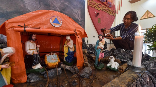 Umat Kristiani merapikan diorama tempat kelahiran Yesus di Gereja Katolik Santo Thomas, Desa Pandan Makmur, Tanjung Jabung Timur, Jambi, Selasa (23/12/2025). [ANTARA FOTO/Wahdi Septiawan/bar]