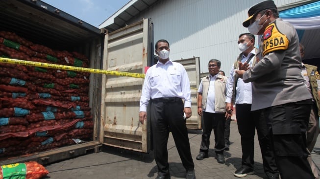 Menteri Pertanian Andi Amran Sulaiman (kiri) didampingi Kapolda Jawa Timur Irjen Pol Nanang Avianto (kanan) meninjau barang bukti saat ungkap kasus pengiriman bawang bombay secara ilegal di salah satu lapangan penumpukan kontainer di kawasan Pelabuhan Tanjung Perak, Surabaya, Jawa Timur, Selasa (23/12/2025). [ANTARA FOTO/Didik Suhartono/bar]