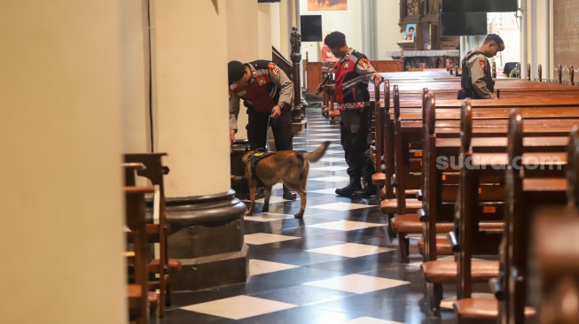 Petugas memeriksa keamanan di Gereja Katedral, Jakarta, Selasa (23/12/2025). [Suara.com/Alfian Winanto]
