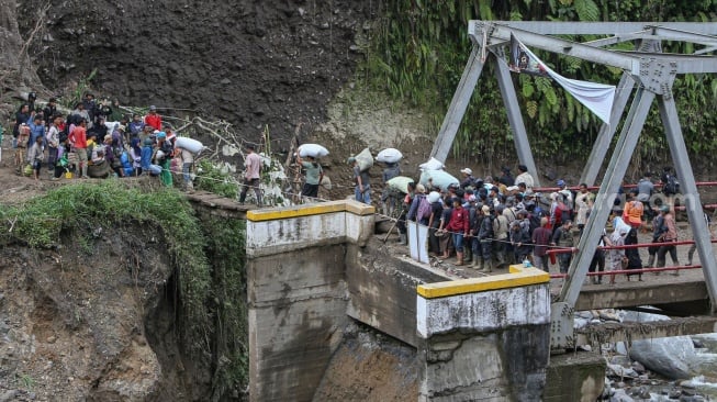 Sejumlah warga menyeberang sungai melalui jembatan darurat di wilayah Tenge Besi, Kecamatan Pintu Rime Gayo, Kabupaten Bener Meriah, Aceh. [Khalis Surry/Suara.com].