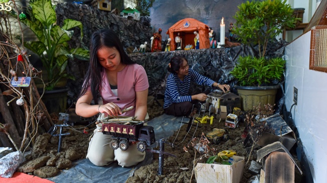 Umat Kristiani merapikan diorama tempat kelahiran Yesus di Gereja Katolik Santo Thomas, Desa Pandan Makmur, Tanjung Jabung Timur, Jambi, Selasa (23/12/2025). [ANTARA FOTO/Wahdi Septiawan/bar]