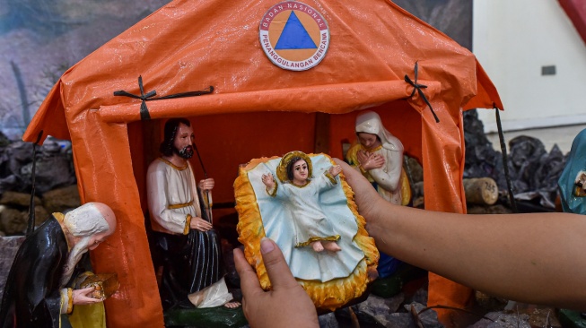 Umat Kristiani merapikan patung bayi Yesus di diorama tempat kelahiran Yesus, Gereja Katolik Santo Thomas, Desa Pandan Makmur, Tanjung Jabung Timur, Jambi, Selasa (23/12/2025). [ANTARA FOTO/Wahdi Septiawan/bar]