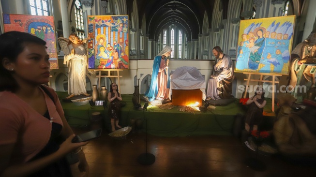 Petugas memasang dekorasi di Gereja Katedral, Jakarta, Selasa (23/12/2025). [Suara.com/Alfian Winanto]
