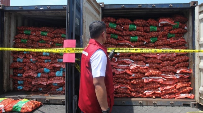 Anggota Ditreskrimsus Polda Jawa Timur menunjukkan barang bukti saat ungkap kasus pengiriman bawang bombay secara ilegal di salah satu lapangan penumpukan kontainer di kawasan Pelabuhan Tanjung Perak, Surabaya, Jawa Timur, Selasa (23/12/2025). [ANTARA FOTO/Didik Suhartono/bar]
