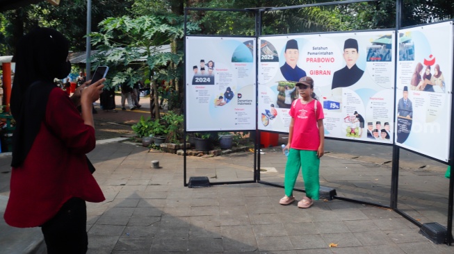 Wisatawan melihat karya foto pada pameran Haluan Merah Putih di Taman Margasatwa Ragunan (TMR) di Jakarta, Kamis (25/12/2025). [Suara.com/Alfian Winanto]
