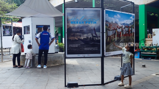 Wisatawan melihat karya foto pada pameran Haluan Merah Putih di Taman Margasatwa Ragunan (TMR) di Jakarta, Kamis (25/12/2025). [Suara.com/Alfian Winanto]
