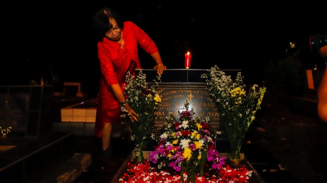 Warga keturunan Portugis saat ziarah makam anggota keluarga mereka pada malam Natal di kompleks Gereja Protestan Indonesia Barat (GPIB) Tugu, Semper Barat, Cilincing, Jakarta, Rabu (24/12/2025).  [Suara.com/Alfian Winanto]