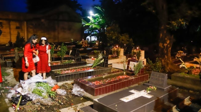 Warga keturunan Portugis saat ziarah makam anggota keluarga mereka pada malam Natal di kompleks Gereja Protestan Indonesia Barat (GPIB) Tugu, Semper Barat, Cilincing, Jakarta, Rabu (24/12/2025).  [Suara.com/Alfian Winanto]