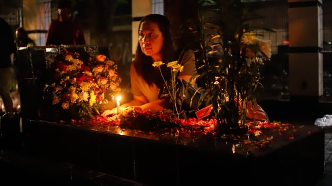 Warga keturunan Portugis menyalakan lilin saat ziarah makam anggota keluarga mereka pada malam Natal di kompleks Gereja Protestan Indonesia Barat (GPIB) Tugu, Semper Barat, Cilincing, Jakarta, Rabu (24/12/2025).  [Suara.com/Alfian Winanto]