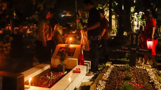 Warga keturunan Portugis saat ziarah makam anggota keluarga mereka pada malam Natal di kompleks Gereja Protestan Indonesia Barat (GPIB) Tugu, Semper Barat, Cilincing, Jakarta, Rabu (24/12/2025).  [Suara.com/Alfian Winanto]
