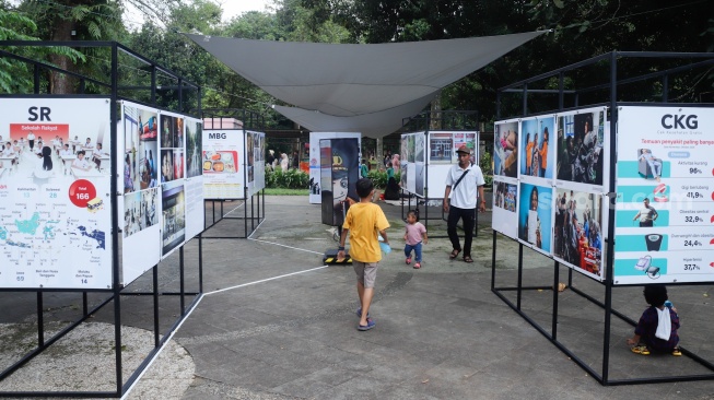 Wisatawan melihat karya foto pada pameran Haluan Merah Putih di Taman Margasatwa Ragunan (TMR) di Jakarta, Kamis (25/12/2025). [Suara.com/Alfian Winanto]
