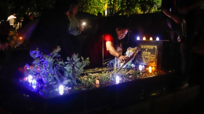 Warga keturunan Portugis saat ziarah makam anggota keluarga mereka pada malam Natal di kompleks Gereja Protestan Indonesia Barat (GPIB) Tugu, Semper Barat, Cilincing, Jakarta, Rabu (24/12/2025).  [Suara.com/Alfian Winanto]