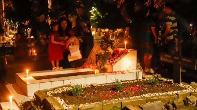 Warga keturunan Portugis saat ziarah makam anggota keluarga mereka pada malam Natal di kompleks Gereja Protestan Indonesia Barat (GPIB) Tugu, Semper Barat, Cilincing, Jakarta, Rabu (24/12/2025).  [Suara.com/Alfian Winanto]