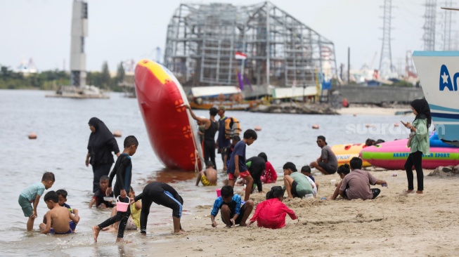 Pengunjung berwisata di Pantai Lagoon, Taman Impian Jaya Ancol, Jakarta, Jumat (26/12/2025). [Suara.com/Alfian Winanto]