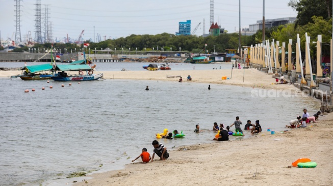 Pengunjung berwisata di Pantai Lagoon, Taman Impian Jaya Ancol, Jakarta, Jumat (26/12/2025). [Suara.com/Alfian Winanto]