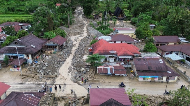 Foto udara warga melewati aliran sungai yang menggenangi jalan pascabanjir bandang susulan di Nagari Maninjau, Agam, Sumatera Barat, Jumat (26/12/2025). [ANTARA FOTO/Iggoy el Fitra/wpa]