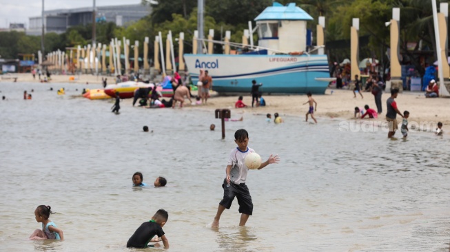 Pengunjung berwisata di Pantai Lagoon, Taman Impian Jaya Ancol, Jakarta, Jumat (26/12/2025). [Suara.com/Alfian Winanto]