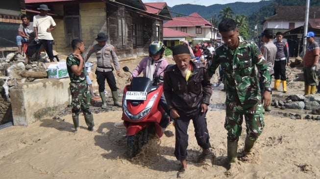 Prajurit TNI membantu warga menyeberang pascabanjir bandang susulan di Nagari Maninjau, Agam, Sumatera Barat, Jumat (26/12/2025). [ANTARA FOTO/Iggoy el Fitra/wpa]