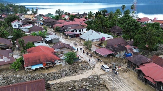 Foto udara warga melewati aliran sungai yang menggenangi jalan pascabanjir bandang susulan di Nagari Maninjau, Agam, Sumatera Barat, Jumat (26/12/2025). [ANTARA FOTO/Iggoy el Fitra/wpa]
