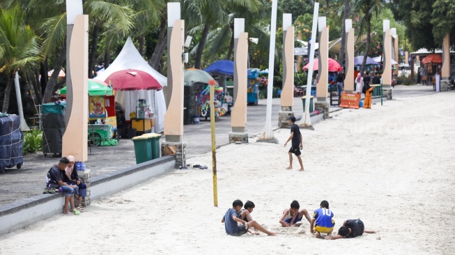 Pengunjung berwisata di Pantai Lagoon, Taman Impian Jaya Ancol, Jakarta, Jumat (26/12/2025). [Suara.com/Alfian Winanto]