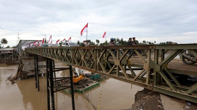 Warga dan kendaraan melewati jembatan darurat bailey Krueng Tingkeum yang baru selesai dibangun di Kuta Blang, Bireuen, Aceh, Sabtu (27/12/2025). (ANTARA FOTO/Irwansyah Putra)