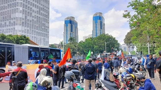 Ratusan buruh dari Konfederasi Pekerja Indonesia (KSPI) mulai melakukan aksi di dekat Istana Merdeka, Jakarta. (Suara.com/Tsabita Aulia)