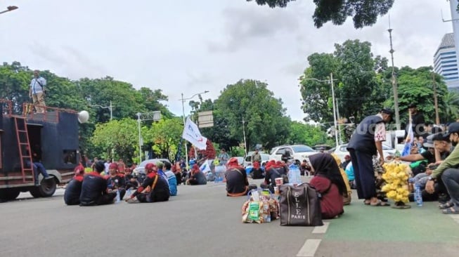 Sejumlah pedagang berjualan di sekitar lokasi demo buruh yang menolak kenaikan UMP di Jakarta Pusat. (Suara.com/ Tsabita Aulia)
