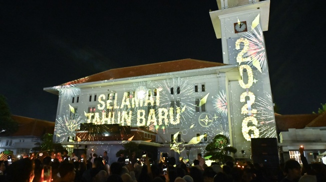Warga menyaksikan pertunjukan video mapping saat malam pergantian tahun baru 2026 di Balai Kota Madiun, Jawa Timur, Kamis (1/1/2026). [ANTARA FOTO/Fikri Yusuf/wpa.]