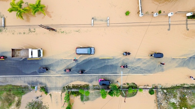 Foto udara mobil dan motor melintasi jalan yang terendam banjir di Desa Tunggulo, Kabupaten Gorontalo, Gorontalo, Senin (5/1/2026). [ANTARA FOTO/Adiwinata Solihin/nz]