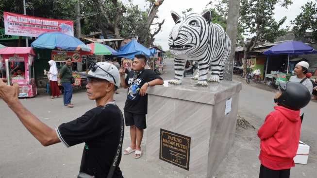 Pengunjung berswafoto di depan patung Macan Putih di Desa Balongjeruk, Kabupaten Kediri, Jawa Timur, Senin (5/1/2026). [ANTARA FOTO/Prasetia Fauzani/nz]