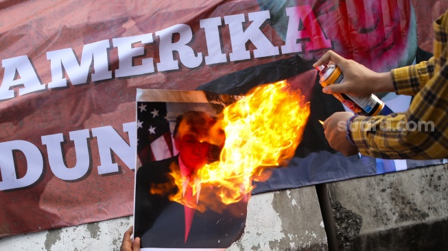 Aktivis dari Free Palestine Network (FPN) membakar foto Donald Trump melakukan aksi bela Venezuela di depan Kedutaan Besar Amerika Serikat, Jakarta, Selasa (6/1/2026). [Suara.com/Alfian Winanto]