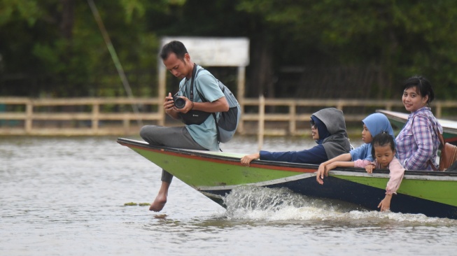 Sejumlah pengunjung menaiki perahu motor untuk mengamati Pesut Mahakam (Orcaella brevirostris) di Desa Wisata Pela di Kutai Kartanegara, Kalimantan Timur, Minggu (4/1/2026). [ANTARA FOTO/M Risyal Hidayat/YU]