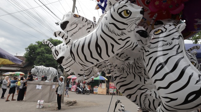 Pengunjung memotret patung Macan Putih dengan latar depan balon menyerupai macan putih di Desa Balongjeruk, Kabupaten Kediri, Jawa Timur, Senin (5/1/2026). [ANTARA FOTO/Prasetia Fauzani/nz]