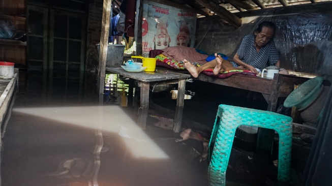 Warga duduk di dalam rumahnya yang tergenang banjir di Pabean, Kota Pekalongan, Jawa Tengah, Rabu (7/1/2026). [ANTARA FOTO/Harviyan Perdana Putra/foc]