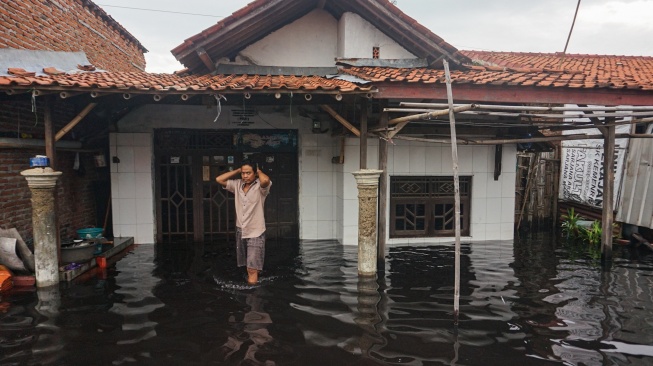 Warga berjalan melewati depan rumahnya yang tergenang banjir di Pabean, Kota Pekalongan, Jawa Tengah, Rabu (7/1/2026). [ANTARA FOTO/Harviyan Perdana Putra/foc]